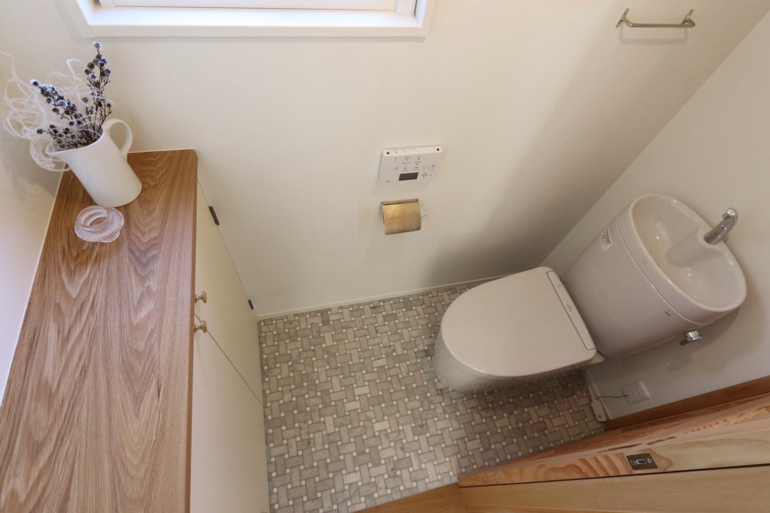 グレーを基調としたトイレは、床にバスケットパターンのマーブルモザイクを採用
