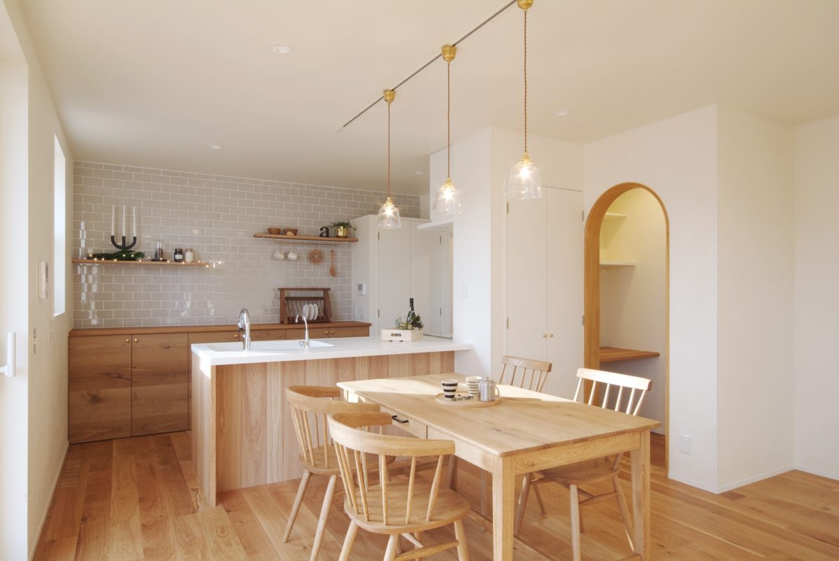 キッチン背面を彩るグレーのサブウェイタイルが光を受けて艶めき、透明感あふれる空間が心地良いシンプルナチュラルの家。